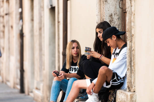 City in Umbria with young people sitting smoking Perugia, Italy - August 29, 2018: City in Umbria with young people sitting by house on summer day smoking little girl smoking cigarette stock pictures, royalty-free photos & images