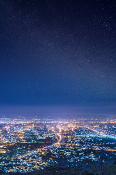 nacht van de stad vanuit het gezichtspunt op de top van berg met close-up detail van de melkweg met sterren achtergrond van een veld, chiang mai, thailand - chiang mai stad stockfoto's en -beelden