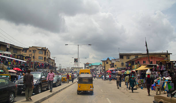 City of Lagos, Nigeria Lagos, Nigeria - May 11, 2012: People and cars in the street, in the city of Lagos, the largest city in Nigeria and the African continent. Lagos is one of the fastest growing cities in the world lagos nigeria stock pictures, royalty-free photos & images