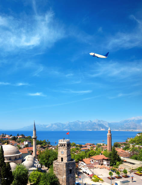 cityscape image of historic district of Antalya and flying airplane over Mediterranean sea and high mountains elevated view of cityscape image of historic district of Antalya over Mediterranean sea and high mountains with clear blue sky in Turkey minaret stock pictures, royalty-free photos & images