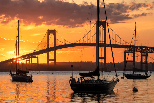 Claiborne Pell Newport Bridge summer sunset Beautiful sunset over the Newport Bridge in August 2020 with 3 moored sailboats in the foreground. newport rhode island stock pictures, royalty-free photos & images