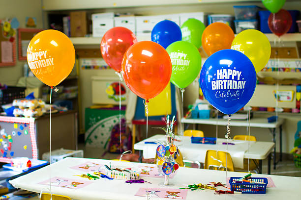 Class or School Birthday Party A classroom decorated with birthday balloons, centerpiece and noisemakers. Background shows typical school supplies and visual and learning aids. classroom party stock pictures, royalty-free photos & images