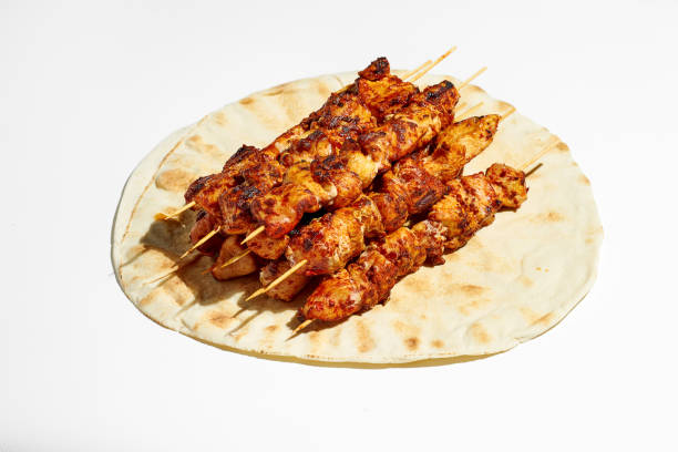 A classic Greek dish is souvlaki, small chicken kebabs. Fast food cooked on skewers and grills. Shish kebab on pita bread on a white background. stock photo