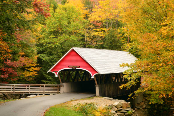 A classic New England Scene The Penigewasset covered birdge is surrounded by brilliant fall foliage near the Flume in Franconia Notch State Park in New Hanpshire covered bridge stock pictures, royalty-free photos & images