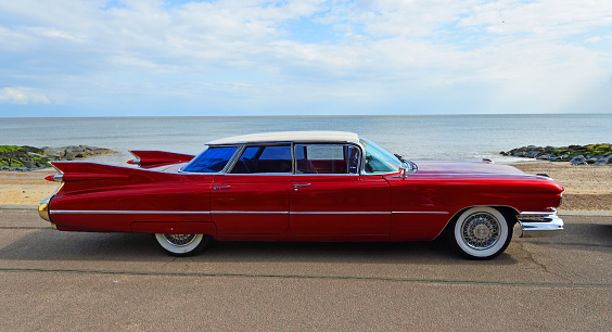 Felixstowe, Suffolk, England - May 05, 2019: Classic Red 1950's 4 door Cadillac  motor car parked on seafront promenade.