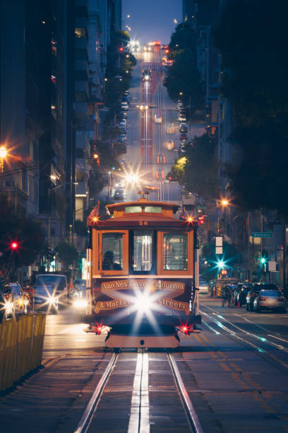 Classic view of historic traditional Cable Cars riding on famous California Street at night with city lights, San Francisco, California, USA Classic view of historic traditional Cable Cars riding on famous California Street at night with city lights, San Francisco, California, USA cable car stock pictures, royalty-free photos & images