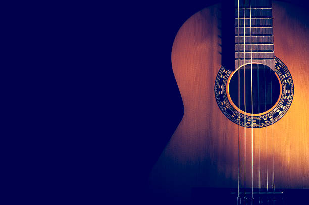 Classical Guitar on a dark background. Classical Guitar on a dark background. Guitar wood is light brown with nice grain. Guitar has nylon strings with a pattern around the sound hole. country and western music stock pictures, royalty-free photos & images
