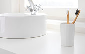 istock Clean bathroom counter with two different bamboo toothbrushes in holder 1312767632