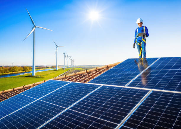 Clean energy concept, photovoltaic panels and wind turbines with a tecnician woman in a rooftop stock photo