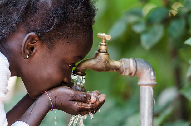 Clean Fresh Water Scarcity Symbol: Black Girl Drinking from Tap stock photo
