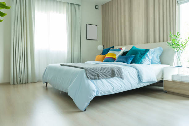 Limpio dormitorio moderno con ajuste de cojín azul y amarillo en él. - foto de stock