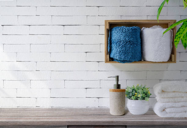 バスルームの棚と木製のテーブルに石鹸ディスペンサー付きのきれいなタオル、白いレンガの壁の背景。 - お手洗い ストックフォトと画像