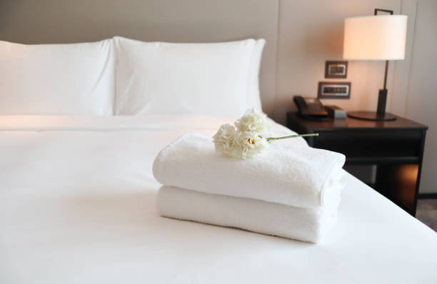 清潔なベッドルームのきれいな白いバスタオル - 居心地の良さとクリーンなコンセプト - 宿屋 ストックフォトと画像