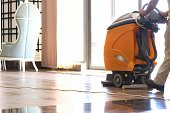 istock Cleaner washing floor in hotel using special machine closeup 1352823793