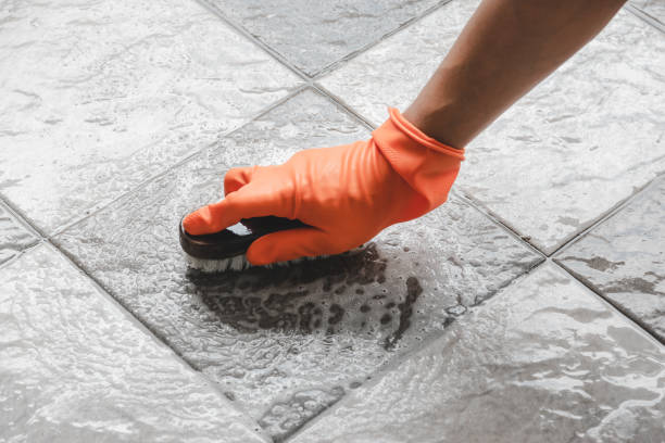 Cleaning Equipment & Supplies Hand of man wearing orange rubber gloves is used to convert scrub cleaning on the tile floor. cleaning cement tiles stock pictures, royalty-free photos & images