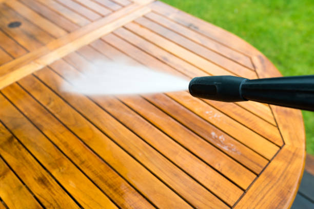 cleaning garden table with a power washer - high water pressure cleaner on wooden exotic table surface stock photo