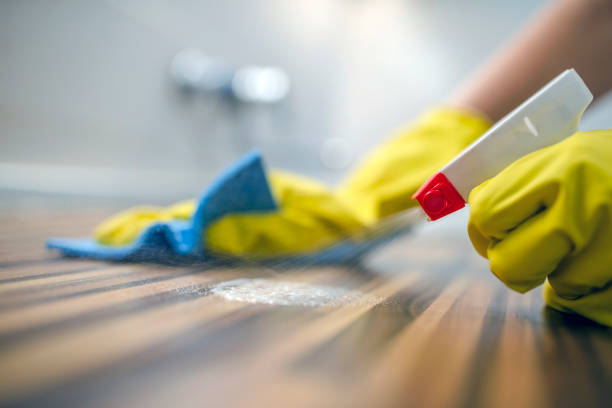 Cleaning kitchen table  with blue cloth Photo of Woman or man cleaning kitchen cabinets with sponge and spray cleaner. Female or male hands Using Spray Cleaner On Wooden Surface. Maid wiping dust while cleaning her house wearing yellow protective gloves, close-up disinfection stock pictures, royalty-free photos & images