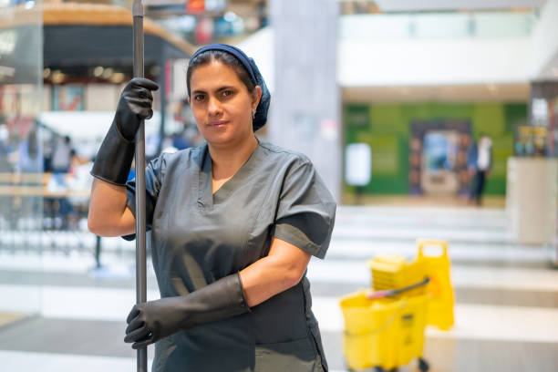 Cleaning lady mopping the floor while working at a shopping mall Portrait of a Latin American cleaning lady mopping the floor while working at a shopping mall and looking at the camera smiling Mall cleaning stock pictures, royalty-free photos & images