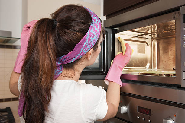 Cleaning oven Girl cleaning oven in the kitchen microwave stock pictures, royalty-free photos & images