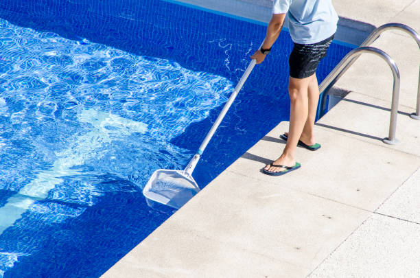 cleaning the swimming pool with a net Boy in flip flops cleaning the swimming pool with a net standing water stock pictures, royalty-free photos & images