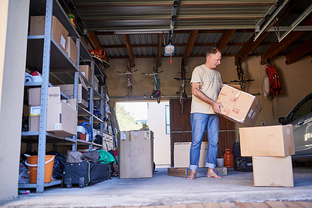 Clearing out some things Shot of a man carrying a box in a garage arrangement stock pictures, royalty-free photos & images