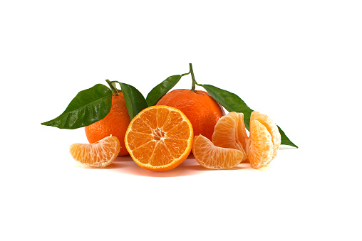 Clementine, tangerine or mandarin orange fruit with green leaves, half-cut citrus fruit and peeled segments lying in front isolated on white background