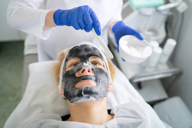 A client is receiving a soothing facial mask, in a beauty salon The beautician is applying a soothing mask onto her client in a modern beauty spa melasma stock pictures, royalty-free photos & images