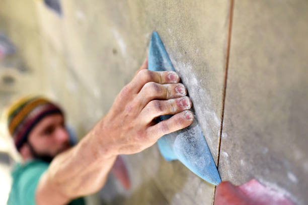 climber bouldering in a sports hall - holding on to the handle of an artificial rock wall climber bouldering in a sports hall - holding on to the handle of an artificial rock wall bouldering stock pictures, royalty-free photos & images