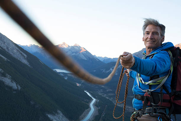 grimpeur tire la corde serrée de son coéquipier - guide photos et images de collection