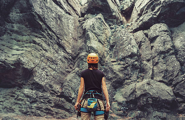 Climber woman standing in front of a stone rock outdoor stock photo