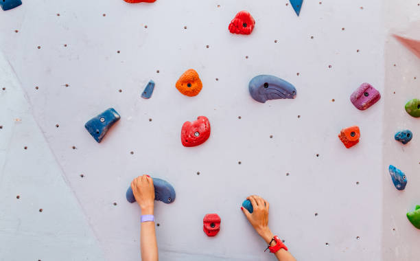 Climber young woman starting bouldering track on artificial wall indoor, hands closeup Climber young woman starting bouldering track on artificial wall indoor, hands closeup bouldering stock pictures, royalty-free photos & images