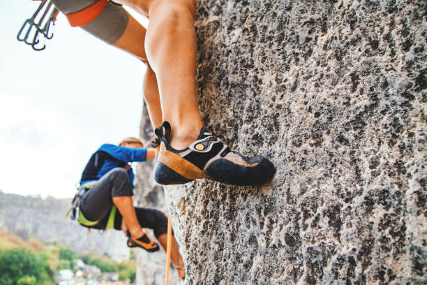 Climbing shoe photo. Cropped frame of female foot in climbing shoe standing on the rock hold. Side view, sport climbing. rock face stock pictures, royalty-free photos & images