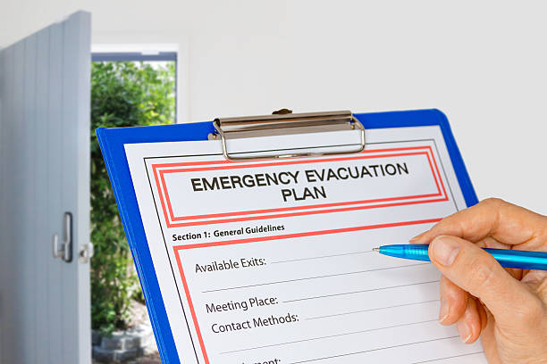 Clipboard with Emergency Evacuation Plan beside Exit Door Hand writing an Emergency Evacuation Plan on clipboard beside Exit Door escaping stock pictures, royalty-free photos & images