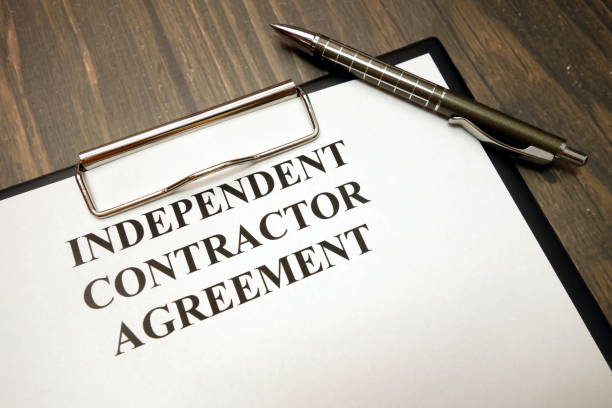 Clipboard with independent contractor agreement and pen on desk Clipboard with independent contractor agreement and pen on wooden desk background independence stock pictures, royalty-free photos & images