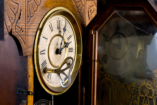 Closeup of the face of an old fashioned clock with the wind-up key inserted