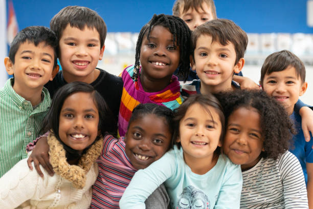 Close friends in class portrait A group of diverse kids smile in this portrait. They are stacked on top of each other while cuddling in close and showing how happy they are. elementary student stock pictures, royalty-free photos & images