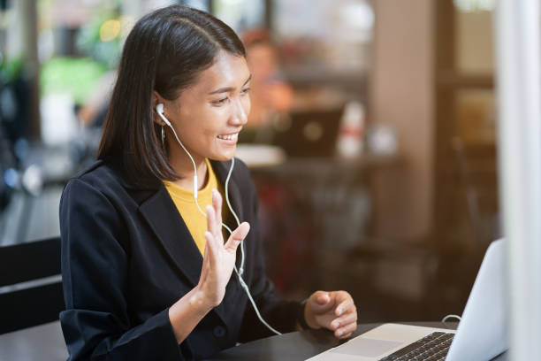 close-up van de aziatische vrouw gebruik oortelefoon aansluiten op laptop en begroeting door videoconferentie praten met vrienden of familie buiten koffie restaurant in ontspannen tijd, levensstijl mensen concept - virtual reality stockfoto's en -beelden