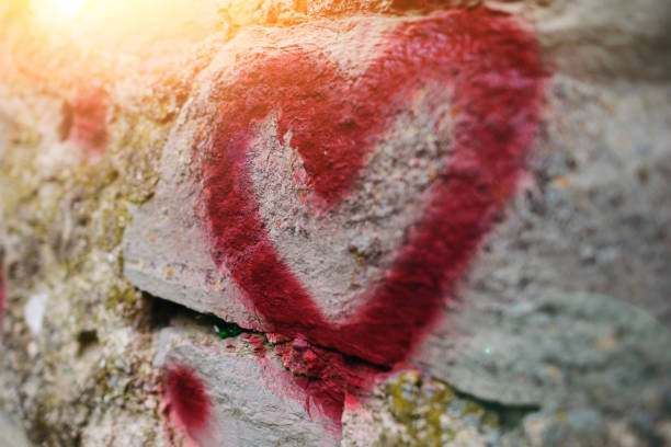 Close up background graffiti silhouette of red heart on an old relief stone wall stock photo