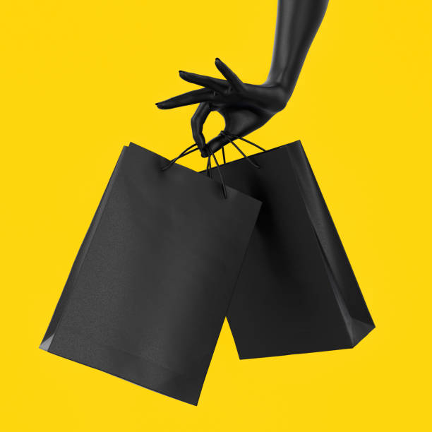Close up black female hand holding black paper bag isolated on yellow background. Shopping and season sale concept template mock-up. Black Friday concept. Copy space. 3d illustration.  black friday shoppers stock pictures, royalty-free photos & images