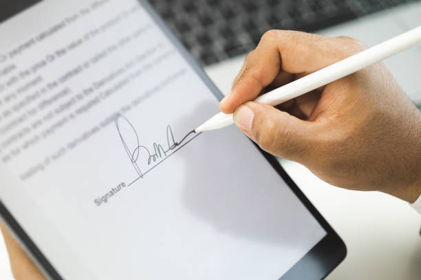 Close up businessman hand electronic Signature on Tablet by Stylus. Write business agreement of contract. Man signing contract on tablet. Business and technology concept. stock photo