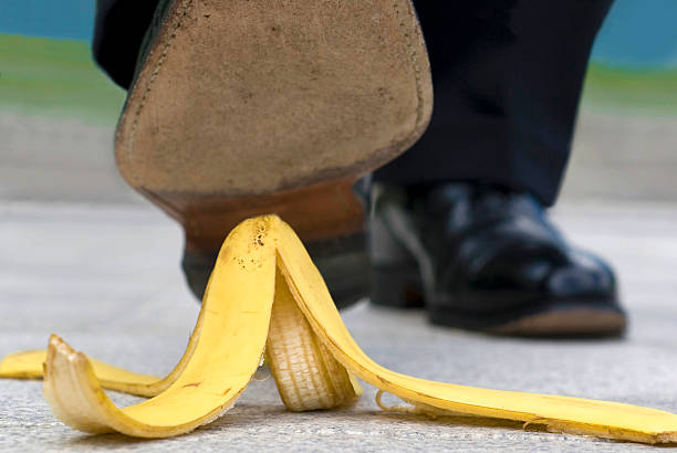 Close up businessman stepping on banana skin stock photo