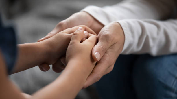 Close up caring mother touching adorable little daughter hands stock photo