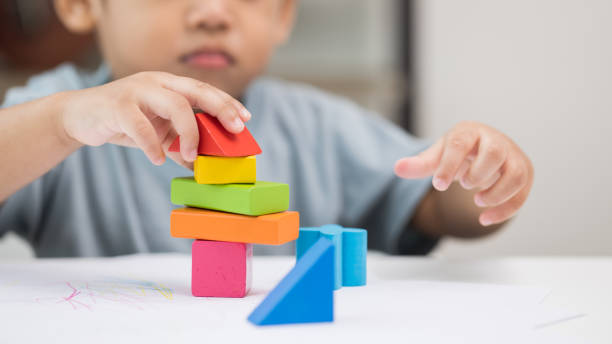 Close up Children hand Practice the skills of playing with wooden toys on the table in living room. Asian little boy education from home. Developing children's learning before entering kindergarten stock photo