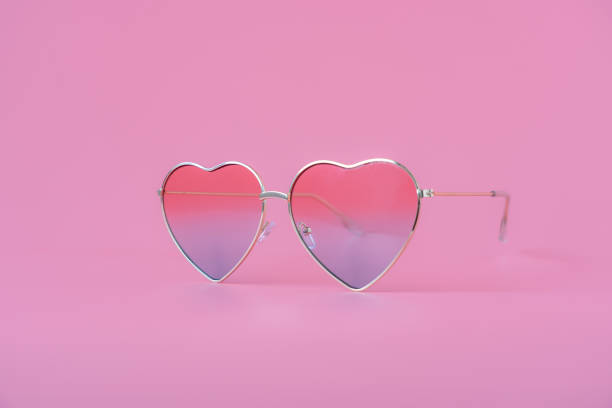 Close up colorful love shape sunglasses on modern rustic pink paper background.pastel tone design & fashion summer concept background. valentine day. stock photo