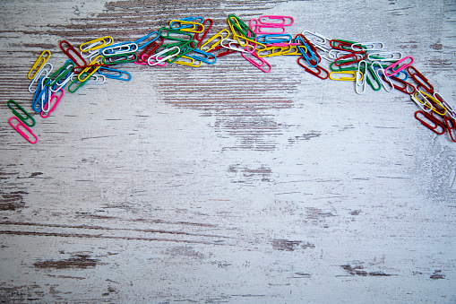 Close up colorful paper clips, office stationary supplies on wooden table for business and work, copy space.