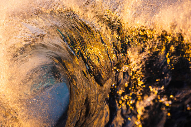 Close up detail of the face of a wave breaking in bright golden light stock photo