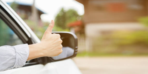 close up driver man hand showing thumb up through car's window for safety and assurance of driving concept. close up driver man hand showing thumb up through car's window for safety and assurance of driving concept. avenue stock pictures, royalty-free photos & images
