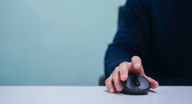 cerrar mano hombre empleado usando el cursor del ratón para desplazarse por la página web o trabajar en el programa informático en el escritorio en el concepto de oficina - computer mouse fotografías e imágenes de stock