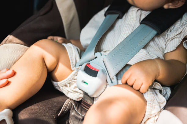 Close up fastening safety belt to baby in car seat. Toddler girl with security belt in vehicle. Safety car. Family travel concept stock photo