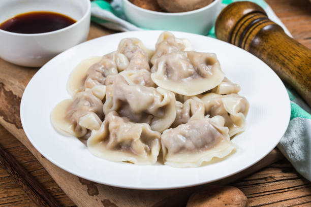 Close up fresh boiled dumplings with hot steams on wood plate. Chinese food on rustic old vintage wooden background. stock photo